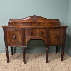 an old fashioned wooden desk with drawers on the top and bottom, against a blue wall