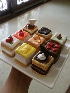 there are many different desserts on the plate and one is being held by someone's hand