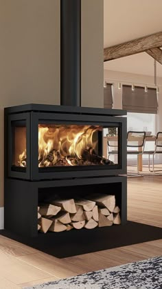 a wood burning stove in a living room next to a pile of firewood on the floor