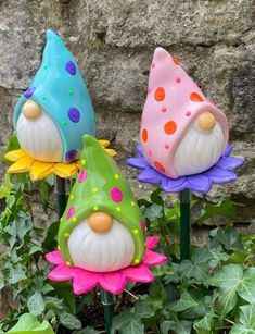 three garden gnomes sitting on top of flowers