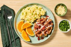 a plate with eggs, bacon, and oranges on it next to other foods