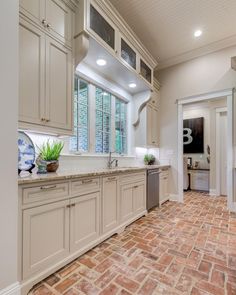 a kitchen with brick flooring and white cabinets in the middle of it is shown