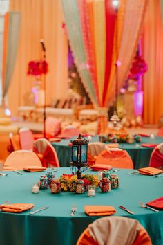 the tables are set up with orange and blue linens for an elegant wedding reception