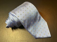 Vintage light blue tie by Monti. The tie is light blue and has a pattern of tiny squares in gold and dark blue. Elegant Light Blue Tie For Black Tie Events, Elegant Light Blue Tie For Formal Occasions, Elegant Light Blue Formal Ties, Elegant Light Blue Formal Bow Tie, Elegant Light Blue Business Ties, Classic Light Blue Formal Ties, Blue Silk Neckwear With Ties, Classic Blue Cotton Tie, Light Blue Tie