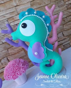 a seahorse cake with pink and purple frosting on it's head, sitting next to a cupcake