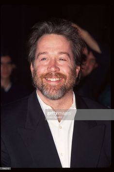 a smiling man in a black suit and white shirt