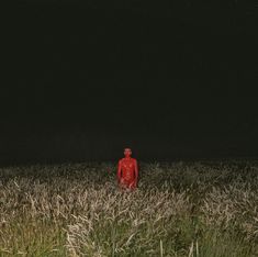 a man standing in the middle of a field at night