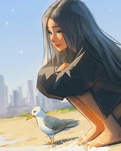 a woman kneeling down next to a seagull on a sandy beach near the ocean