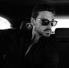 a man wearing sunglasses sitting in the back seat of a car