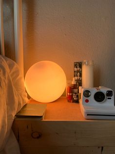 a white lamp sitting on top of a wooden table next to a camera and other items