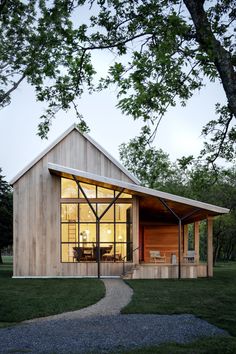 a small wooden house sitting on top of a lush green field next to a tree