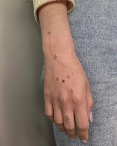 a woman's left hand with small stars and moon tattoos on her left wrist