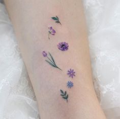 a woman's foot with purple flowers on it and green leaves coming out of the flower