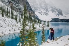 a man and woman standing on top of a snow covered mountain