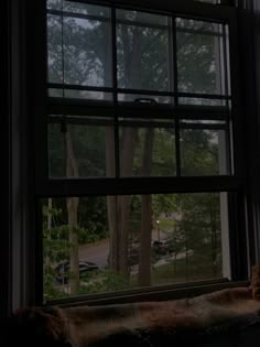 an open window in a dark room with trees outside