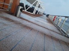 the deck of a cruise ship with no people on it and water in the background