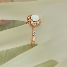 a white opal and diamond ring sitting on top of a table