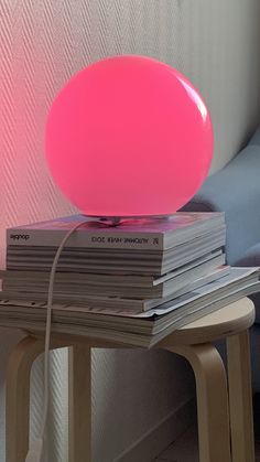 a pink lamp sitting on top of a stack of books