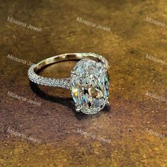 an oval cut diamond ring sitting on top of a table