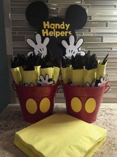 two buckets filled with black and yellow mickey mouse hats sitting on top of a counter