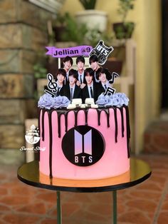 a cake decorated with the band bt's on top of a table in front of a brick wall