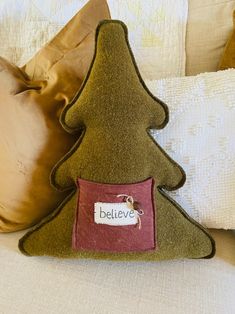 a pillow with a believe sign on it and a christmas tree shaped pillow in the shape of a house