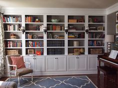 a living room filled with lots of bookshelves next to a piano in front of a window