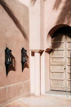 two black lights are on the side of a pink building with a door and window