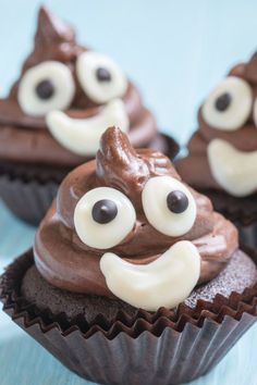 chocolate cupcakes decorated with googly eyes and white frosting on a blue surface