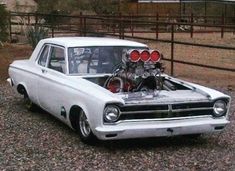 an old white car parked in front of a fence