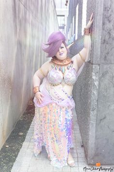 A fairy with purple hair and iridescent purple outfit leans against a wall smiling. Plus Size Zelda Cosplay, Great Fairy Cosplay Botw, Zelda Great Fairy Cosplay, Purah Zelda Tears Of The Kingdom Cosplay, Great Fairy Zelda Breath Of The Wild, Zelda's Ballad Outfits, The Great Fairy Zelda, Link Cosplay Breath Of The Wild, Great Fairy Zelda