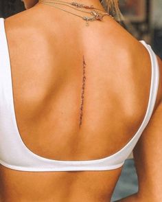 the back of a woman's white top with writing on her left shoulder and lower back