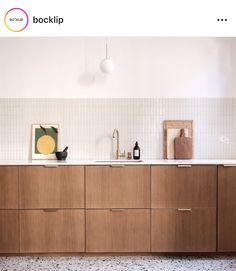 a kitchen with wooden cabinets and white tile on the wall above it is an art work