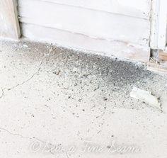 a bottle that is sitting on the ground next to a door with dirt all over it