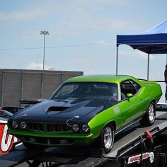 a green and black muscle car parked on top of a flatbed truck