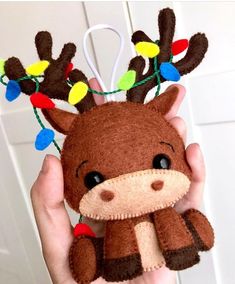 a hand holding a stuffed animal with christmas lights on it's antlers and nose