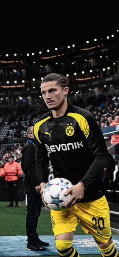 a man holding a soccer ball while standing on top of a field in front of a crowd