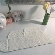 a crocheted heart shaped placemat next to a vase with flowers in it