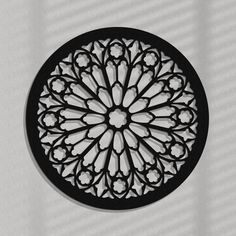 a clock that is on the side of a wall with a flower design in black and white