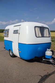 a blue and white trailer parked on the side of a road next to a field