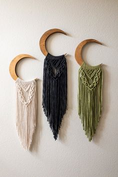 three wall hangings with different colors and designs on them, one is made out of wood