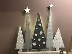 three wooden christmas trees on top of a radiator in front of a wall