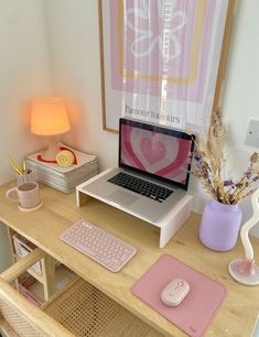 a laptop computer sitting on top of a wooden desk next to a pink mouse pad