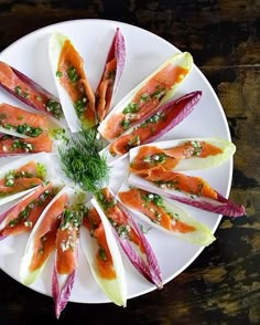 a white plate topped with lots of food on top of a wooden table next to a knife