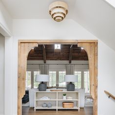 an open living room with white walls and wooden beams, two lamps on either side of the fireplace