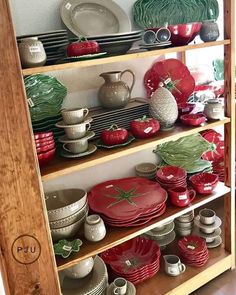 a wooden shelf filled with lots of red and white dishes on top of each other