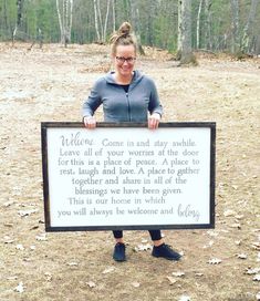 a woman standing in the woods holding a sign