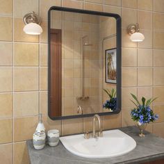 a bathroom sink sitting under a mirror next to a vase with blue flowers on it