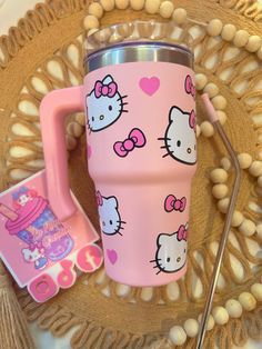 a pink hello kitty travel mug next to a straw on a doily place mat