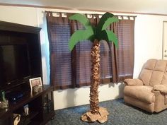 a living room with a couch, chair and palm tree in the middle of it